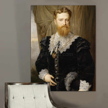 Load image into Gallery viewer, A portrait of a man with a beard dressed in black royal clothes hangs on the gray wall above the chair