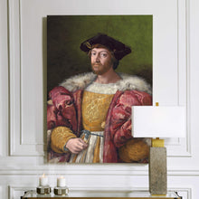 Load image into Gallery viewer, A portrait of a man dressed in pink royal attire with fur hangs on a white wall above a candle