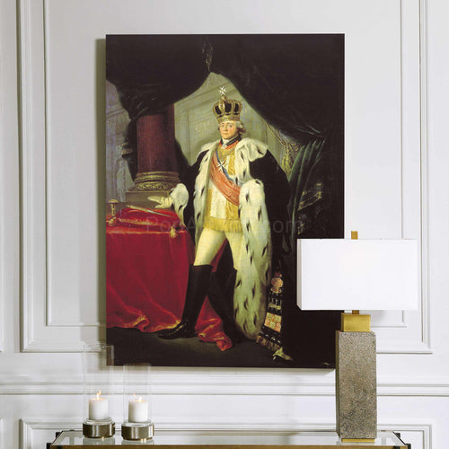 A portrait of an elderly man dressed in gold royal attire with a crown hangs on a white wall next to a lamp