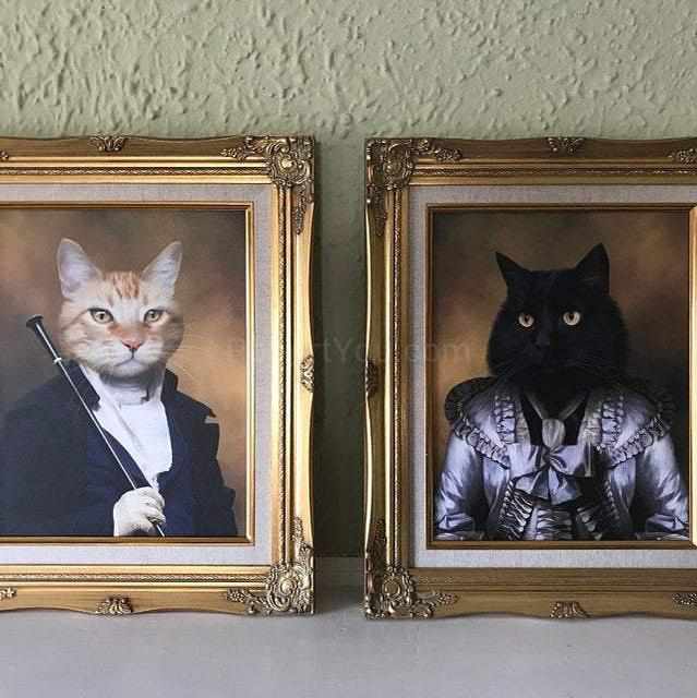 Two framed portraits of cats in historical attires stand next to a light-colored wall