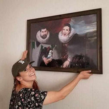 Load image into Gallery viewer, A woman with a smile on her face is holding a portrait of herself with her married couple dressed in black royal clothes

